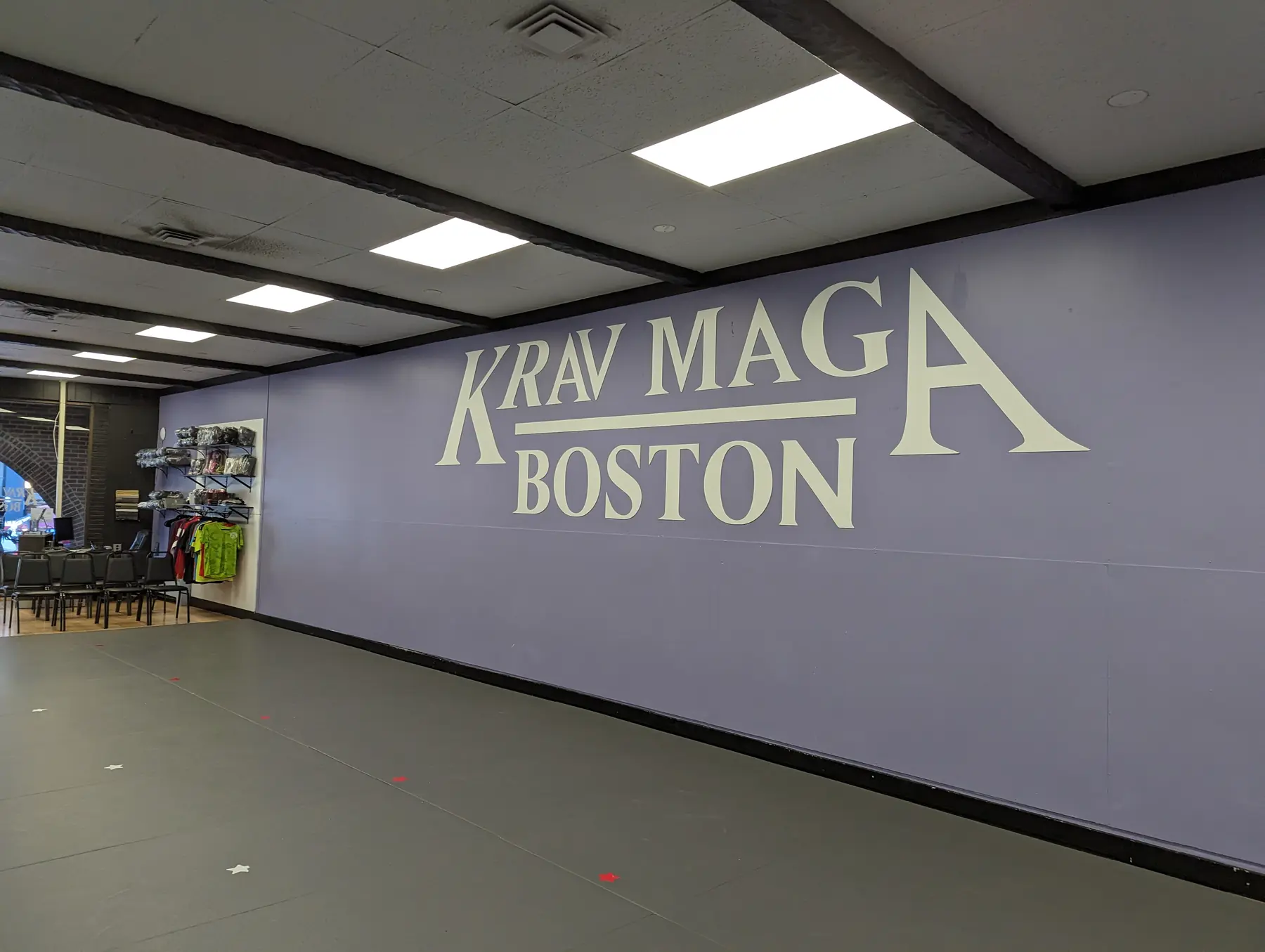 Large Krav Maga Boston logo installed across a purple training room wall