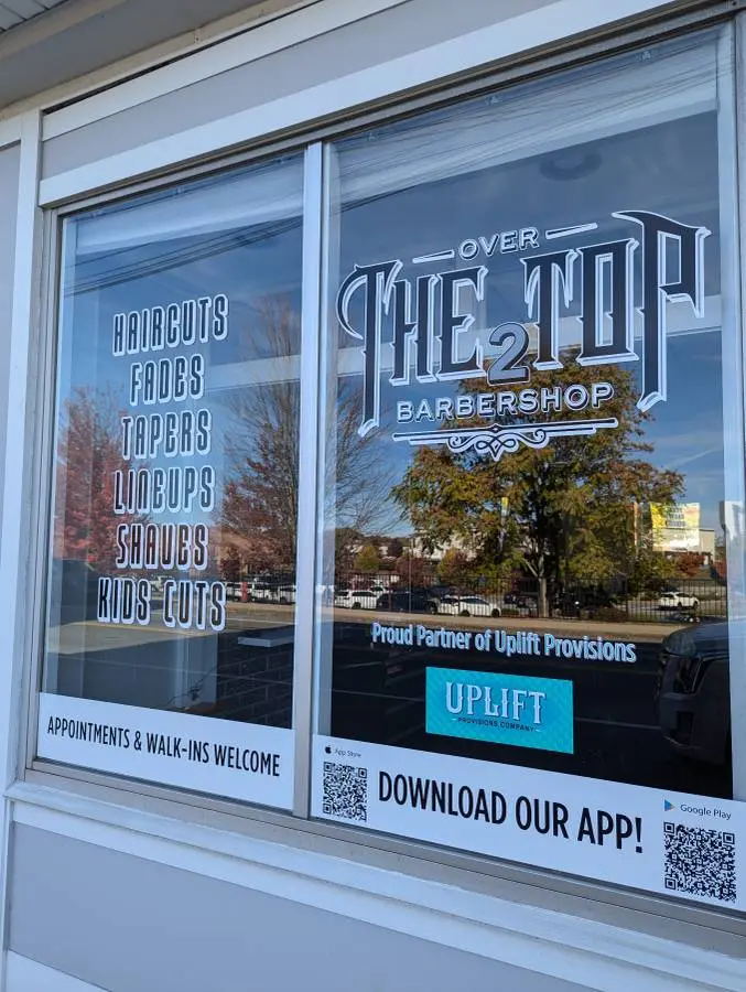 The UpLift Barbershop storefront window with completed lettering and graphics